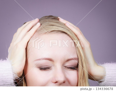 Happy blonde woman holding head out of joy Happy blonde woman holding head out of joy 134336678