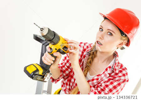 Woman using drill on ladder Woman using drill on ladder 134336721