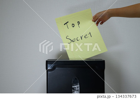 極秘と書かれた書類をシュレッダーにかける手 134337673