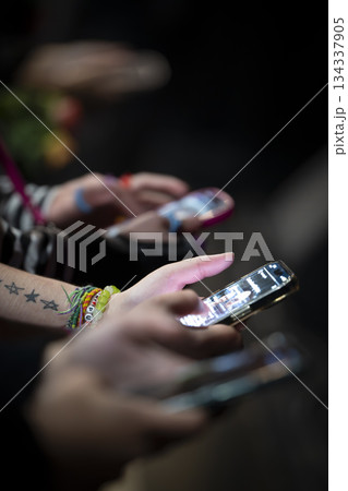 Hands using smartphones during a social event at night Hands using smartphones during a social event at night 134337905