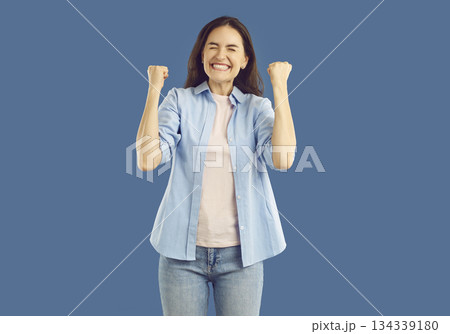 with raised fists. Handsome satisfied man celebrating success, expressing positive emotions over isolated studio background 134339180