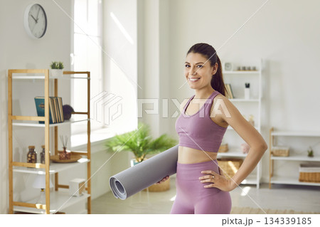 Happy slim sporty woman going to do sport exercises holding yoga mat in hands at home. 134339185
