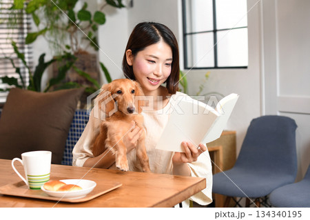 自宅で犬と読書するアジア人の若い女性 自宅で犬と読書するアジア人の若い女性 134340195