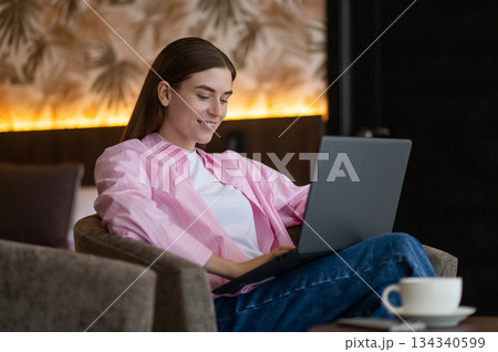 Pretty long-haired woman with a laptop in a hotel room Pretty long-haired woman with a laptop in a hotel room 134340599