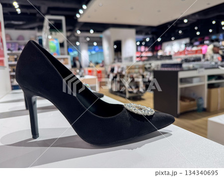 Elegant black high heel shoe with decorative detail displayed in modern fashion store 134340695