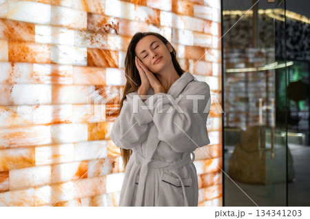Pretty woman in white bath robe feeling relaxed and peaceful after spa procedures Pretty woman in white bath robe feeling relaxed and peaceful after spa procedures 134341203