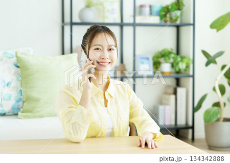 リビングでスマホで通話する笑顔の日本人女性のポートレート 134342888