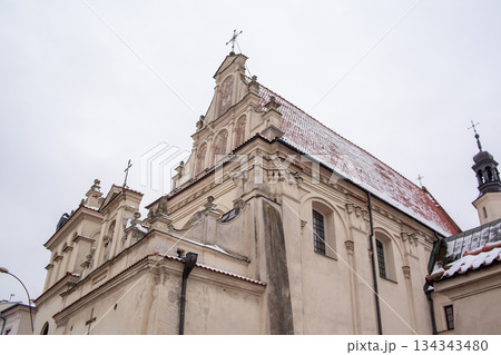 Snow covers the rooftop of a historical church in a small town during winter 134343480