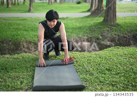 Man rolling exercise mat outdoors Man rolling exercise mat outdoors 134343535