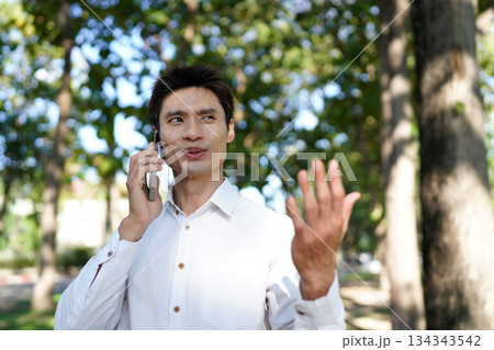 Man talking on phone in park 134343542