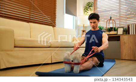 Man exercising with resistance band at home 134343543