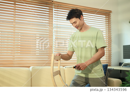 A man assembling new rocking armchair at home with screwdriver, DIY home improvement A man assembling new rocking armchair at home with screwdriver, DIY home improvement 134343596