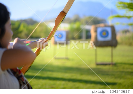 Woman practicing archery at straw targets outdoors 134343637