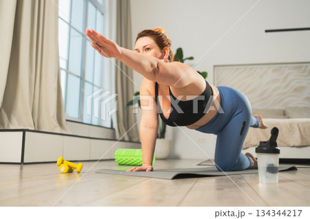 Yoga fitness workout training. Woman practicing yoga at home. Plus size female doing sports exercise on yoga mat indoor. Girl in sportswear have training workout for weight loss. Sport and fitness Yoga fitness workout training. Woman practicing yoga at home. Plus size female doing sports exercise on yoga mat indoor. Girl in sportswear have training workout for weight loss. Sport and fitness 134344217