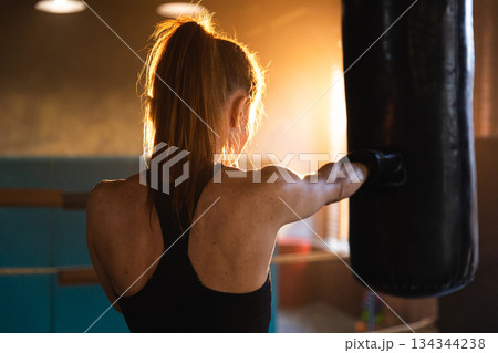 Women self defense girl power. Strong woman fighter training punches on boxing ring. Healthy strong girl punching boxing bag. Training day in boxing gym. Strength fit body workout training Women self defense girl power. Strong woman fighter training punches on boxing ring. Healthy strong girl punching boxing bag. Training day in boxing gym. Strength fit body workout training 134344238