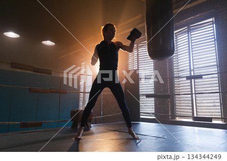 Women self defense girl power. Strong woman fighter training punches on boxing ring. Healthy strong girl punching boxing bag. Training day in boxing gym. Strength fit body workout training 134344249