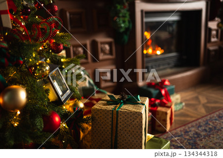 Many gift boxes in classical Christmas decorated interior living room library with fireplace. Christmas gift near fir tree. Modern classic style interior design apartment. Christmas eve at home Many gift boxes in classical Christmas decorated interior living room library with fireplace. Christmas gift near fir tree. Modern classic style interior design apartment. Christmas eve at home 134344318