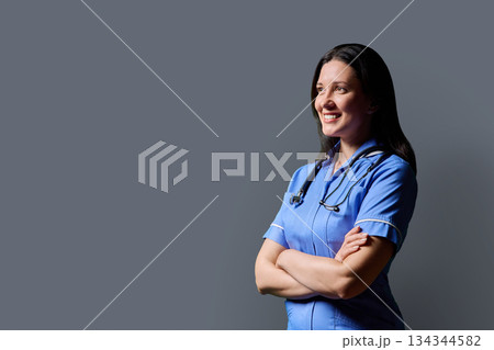 Profile portrait of confident middle-aged woman doctor, nurse on grey background Profile portrait of confident middle-aged woman doctor, nurse on grey background 134344582