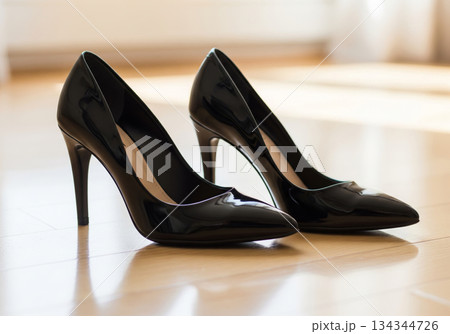 明るい自然光が当たるフローリングに置かれた黒い光沢のハイヒール 明るい自然光が当たるフローリングに置かれた黒い光沢のハイヒール 134344726