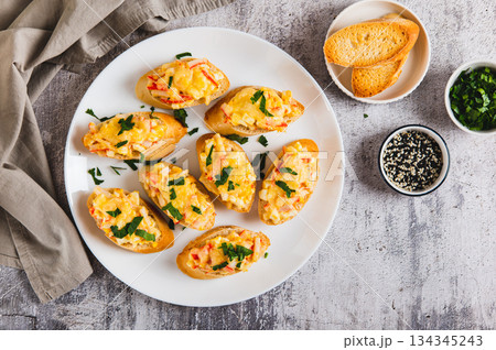 Mini baked sandwiches with crab sticks, egg and cheese on a plate on the table top view 134345243