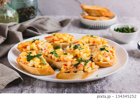 Mini baked sandwiches with crab sticks, egg and cheese on a plate on the table Mini baked sandwiches with crab sticks, egg and cheese on a plate on the table 134345252