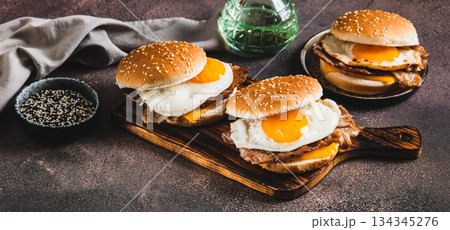 Burgers with fried egg, bacon and cheese on a board on a table web banner 134345276