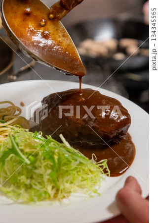 デミグラスソースをかけるハンバーグのクローズアップ 134345565