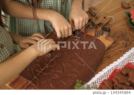 Children carve Christmas figures out of ginger dough and cookies. Festive preparations for Christmas and New Year 134345864