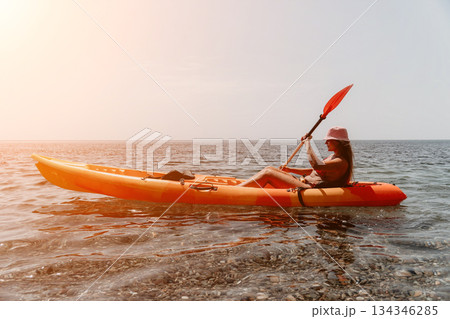 Woman Kayak Paddle Sea - Woman enjoys kayaking in the sea during sunset. 134346285