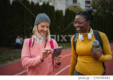 Two diverse adult women checking phone during track walk Two diverse adult women checking phone during track walk 134346882