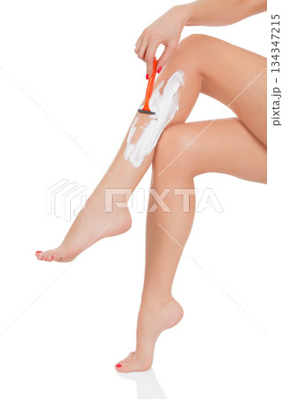 Woman shaving her legs, white background Woman shaving her legs, white background 134347215
