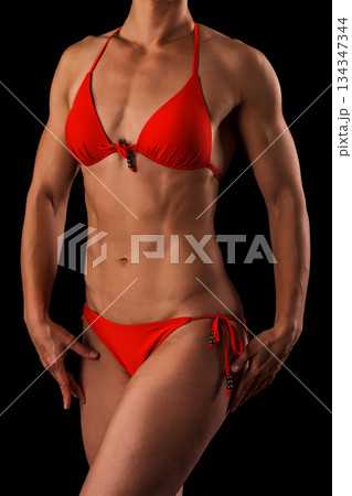 Muscular female body against black background. Muscular female body against black background. 134347344