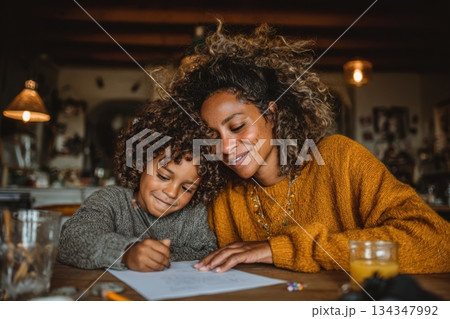 Black mother guiding child in home-school activity 134347992