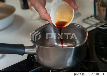 鍋に調味料を加える調理工程のクローズアップ 134348161