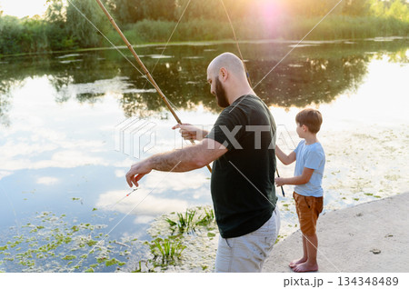 Father and son fishing together at river during sunset Father and son fishing together at river during sunset 134348489
