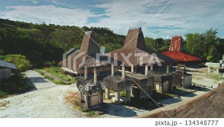 Ancient megalithic tombs and traditional houses with thatched roofs stand as testaments to the rich cultural heritage of Sumba Island. Indonesia. Creating a captivating scene under the clear blue sky Ancient megalithic tombs and traditional houses with thatched roofs stand as testaments to the rich cultural heritage of Sumba Island. Indonesia. Creating a captivating scene under the clear blue sky 134348777