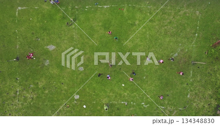 Fiji islands: Aerial view of Fijian children playing soccer on a vibrant green field, showcasing the joy of sports in a tropical setting. Drone flight Fiji islands: Aerial view of Fijian children playing soccer on a vibrant green field, showcasing the joy of sports in a tropical setting. Drone flight 134348830