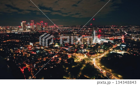 England, London: Breathtaking aerial view of night London city, highlighting the illuminated skyline skyscrapers and vibrant lights of Canary Wharf. Drone flight panorama over modern urban landscape 134348843