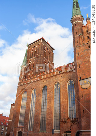 Historic brick church with tall tower under blue sky in city setting 134349239