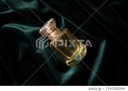 Fragrance bottle with faceted cap resting on luxurious emerald green velvet Fragrance bottle with faceted cap resting on luxurious emerald green velvet 134350264