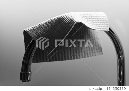 a textured cleaning cloth draped over a curved chrome bar 134350389