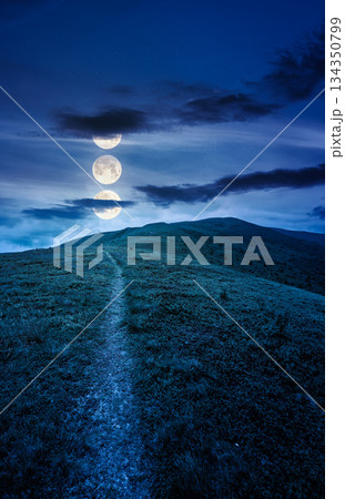 hiking trail through mountain landscape at night. mountains under sky with clouds in full moon light. scenery with green grass and rolling hills. questionable finance investment or abstract concepts 134350799