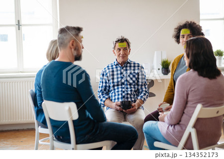 Group of people sitting in a circle and sharing experiences during guided therapeutic session. 134352173