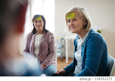 Senior woman identifying emotions during group therapy session. Senior woman identifying emotions during group therapy session. 134352175