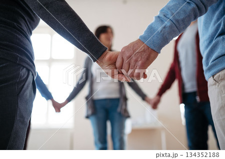 Group of people standing in a circle and holding hands during therapy. Group of people standing in a circle and holding hands during therapy. 134352188
