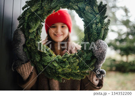 Girl holding a handmade Christmas wreath. 134352200