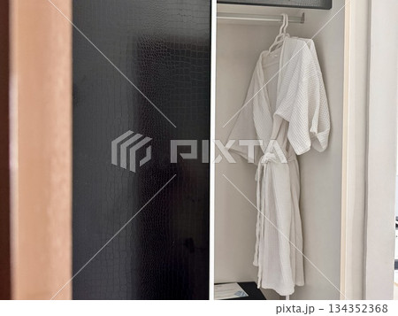 A clean white waffle bathrobe is hanging on a hanger in the hotel closet. High quality photo A clean white waffle bathrobe is hanging on a hanger in the hotel closet. High quality photo 134352368