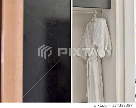 A clean white waffle bathrobe is hanging on a hanger in the hotel closet. High quality photo A clean white waffle bathrobe is hanging on a hanger in the hotel closet. High quality photo 134352387