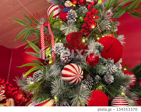 Detailed view of Christmas tree with red ornaments and pinecones. Seasonal decoration, festive texture and classic holiday styling. 134353370