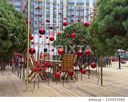 Christmas Outdoor seating area under red ornament light canopy. Festive winter cafe space, holiday decor and cozy seasonal atmosphere Christmas Outdoor seating area under red ornament light canopy. Festive winter cafe space, holiday decor and cozy seasonal atmosphere 134353560